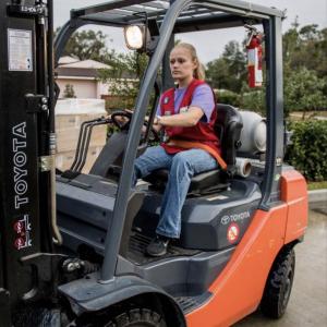 tractor supply employee in a red vest, driving a forklift