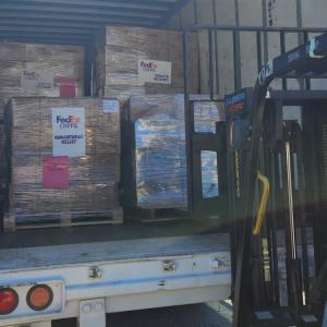 a trailer full of pallets marked with FedEx Cares, humanitarian relief. a person looking in.
