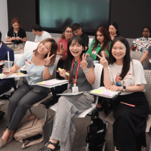 Students in chairs, some smiling and giving a peace sign to the camera.