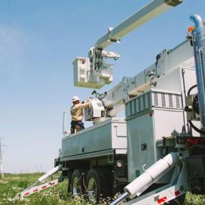 A power utility vehicle parked near tall power-line towers.