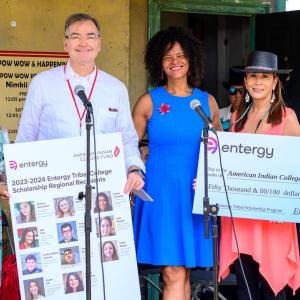 Five people posed with a large check and profiles of scholarship winners.