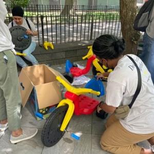 people outside assembling small tricycles