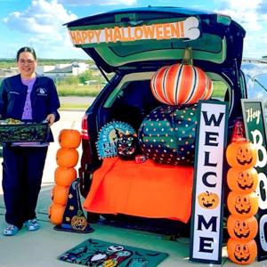 Angelica next to an open car trunk decorated for halloween.
