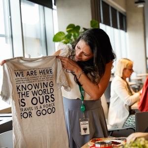 A person holding us a tshirt "...Knowing the world is ours..." and other writing on it.