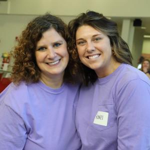 Two smiling people in matching purple shirts