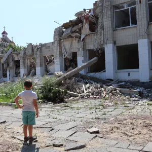 A boy stands in front of a school in the city of Zhytomyr that was destroyed by a Russian missile strike in March 2022. (Nick Allen/Direct Relief)