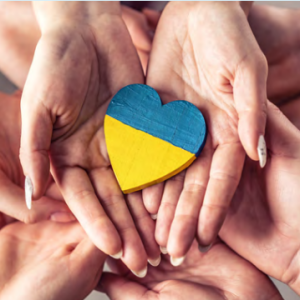 Many hands holding a a blue and yellow heart.