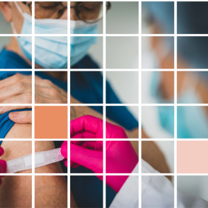 A medical provider in ppe puts a band-aid on the arm of another person wearing a protective mask.