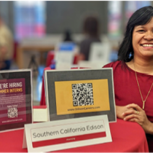 A person leaning on a high stand with displays referring to hiring and applying at SCE.