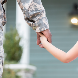 person in military uniform holds child hand