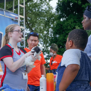 A worker holding a puppy and speaking with people