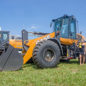 A person standing by a large bucket-style construction vehicle.