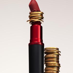 A lipstick with stacked coins in the middle of it and to the side.