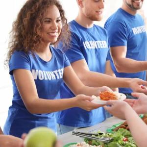 A line of volunteers handing food to others.