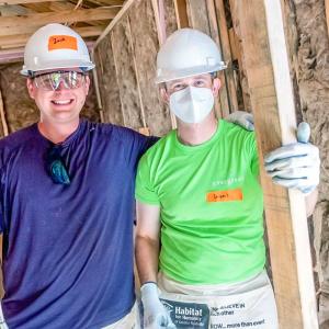 Two people posed in a house under construction.