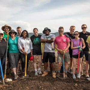 Group of volunteers stood together for a photo while holding gardening tools 