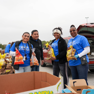 Volunteers packing bags of food into the back of a vehicle.