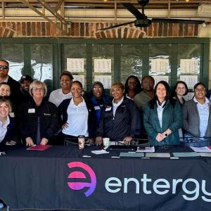 A group posed behind a table with "entergy" sign in front.