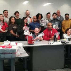 A group posed behind desks, holding bags.