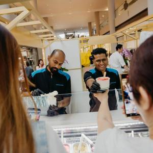 Two volunteers serving ice cream to others.