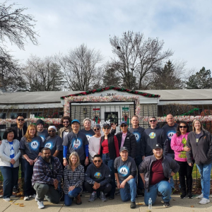 A group of volunteers in front of a fence and building.
