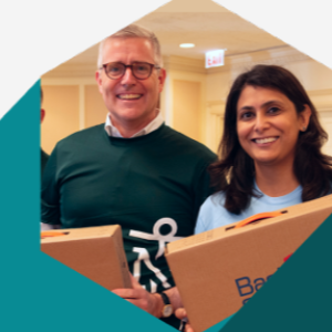 Two smiling people holding boxes.