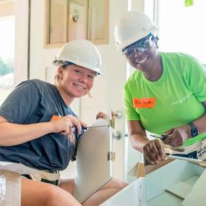 Two smiling people building.
