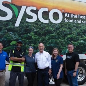 Team of volunteers in front of a truck with Sysco logo on the side.