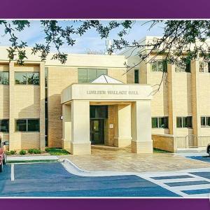 Exterior of a "Hall" with cars parked in spaces outside of it.