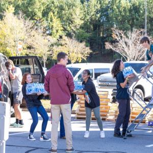 people in a line passing packs of water bottles