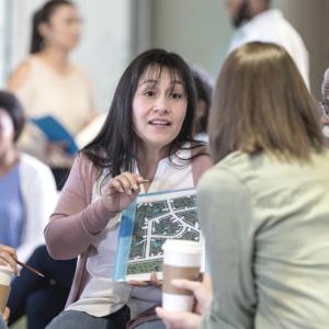 a group of people sitting, talking, one showing a map to the others