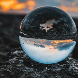 A clear sphere on dark ground. Cloudy sky in the background.
