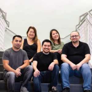 A group of five posed seated on a staircase.