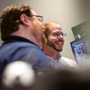 Two people smiling and looking at screens