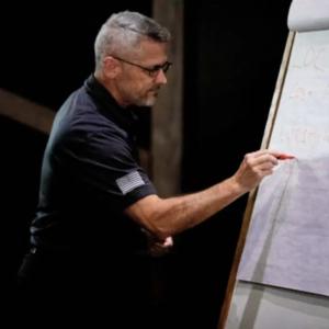 A person drawing on a paper board at the front of a room.