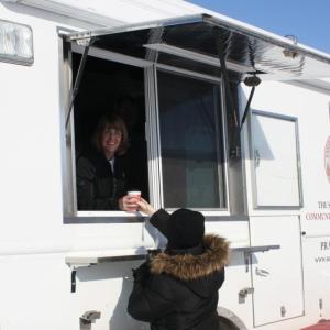 Debbie Clarke serving a coffee out of the side of the white CRU truck