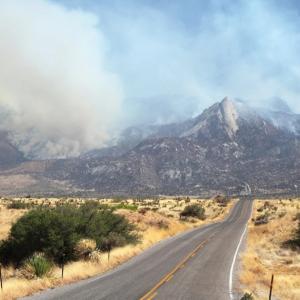 A mountain and desert landscape, billowing smoke from the hills