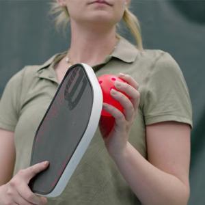 A person holding a pickleball racket and ball