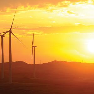 three wind turbines with a setting sun in the background