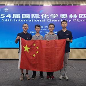 Four people stand holding a Chinese flag