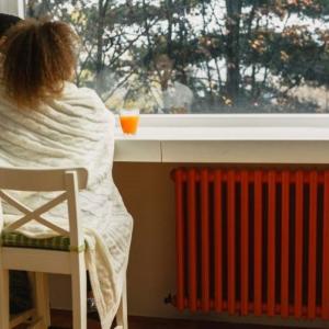 two people sharing a blanket at home, gazing out through a window
