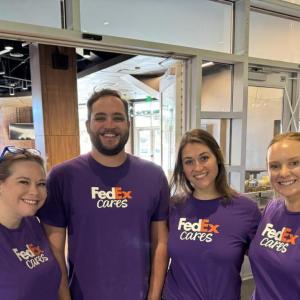 Four smiling people in FedEx Cares t-shirts