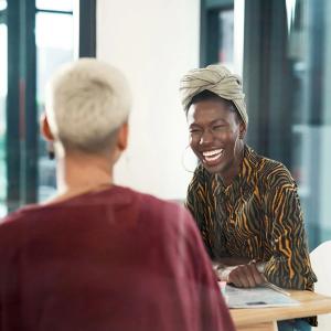 Two people seated at a table, glass walls behind them