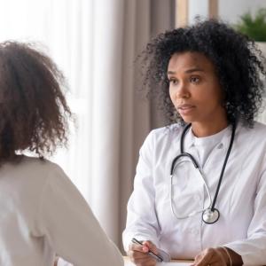 two people talking across from each other, wearing white lab coats, one has a stethoscope around their neck