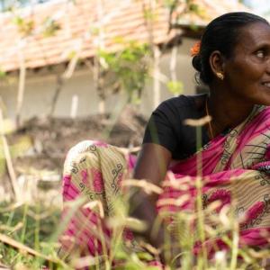 a person in a garden, a house behind them