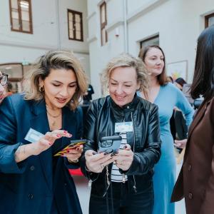 Women dressed in business attire eagerly looking at phones