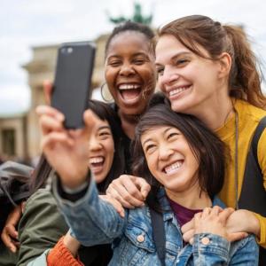Four smiling people taking a selfie together outside