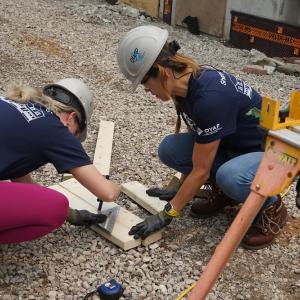 Two volunteers measuring a piece of wood.