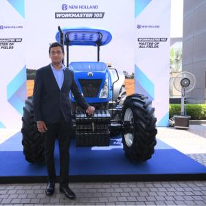 A person standing next to a blue tractor on display.