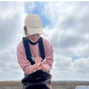 person writing in a notebook in a field